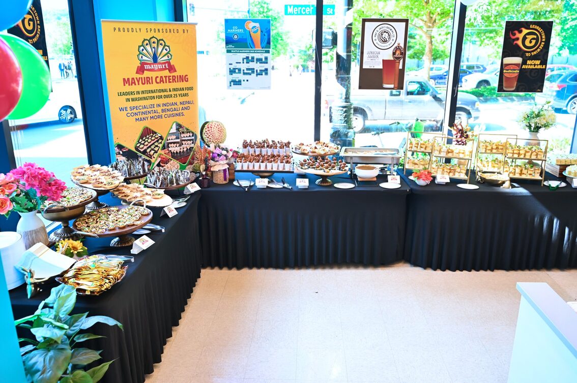 Mayuri catering stand set up at an event with signage and flowers